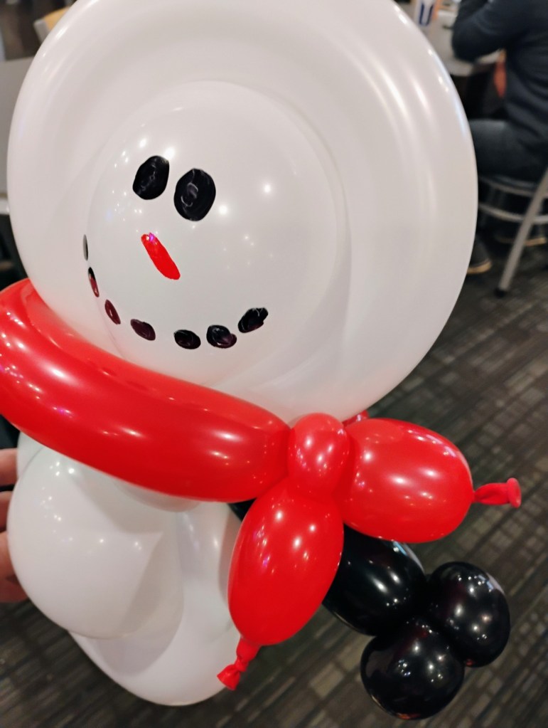 White balloon snowman with a bright red scarf and black balloon boots